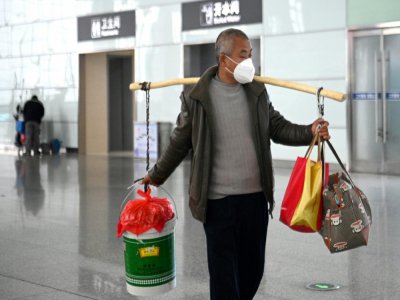 Un homme porte des sacs de provisions à la gare de Hefei, le 10 mars 2020 dans l'est de la Chine - Noel Celis [AFP]