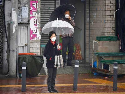 Une femme dans une rue de Daegu, en Corée du Sud, porte un masque de protection pour lutter contre la propagation du Covid-19, le 10 mars 2020 - ED JONES [AFP]