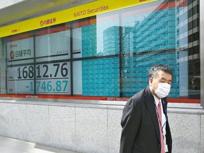 Un homme masqué passe devant un écran de la Bourse de Tokyo en chute, le 13 mars 2020 - Philip FONG [AFP]