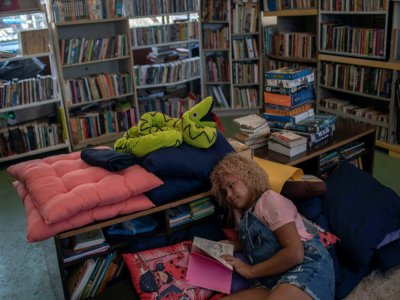 La jeune Brésilienne Lua Oliveira, 12 ans, lit dans la bibliothèque qu'elle a fondée, dans la favela de Tabajaras à Rio de Janeiro, le 10 mars 2020 - MAURO PIMENTEL [AFP]