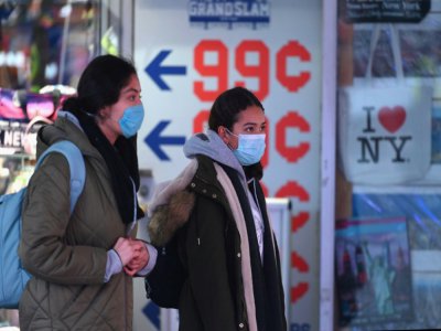 Deux femmes portant un masque contre le coronavirus traversent Times Square, le 12 mars 2020 - Angela Weiss [AFP]