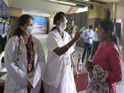 Des membres du personnel médical vérifie la température d'une visiteuse au Centre d'exposition et de conférence de l'aéroport Begumpet, le 13 mars 2020 à Hyderabad, en Inde - NOAH SEELAM [AFP]