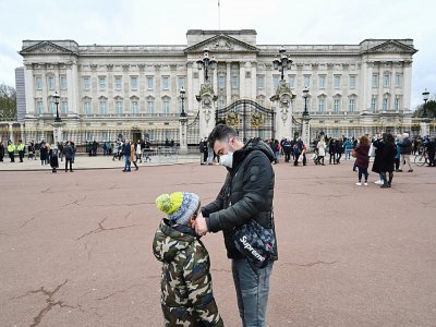 Un père ajuste le masque de protection de son fils, le 14 mars 2020 à Londres - Glyn KIRK [AFP]