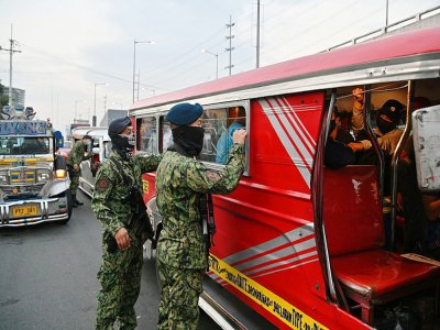 Un policier philippin inspecte un bus à Manille, le 15 mars 2020 - Ted ALJIBE [AFP]