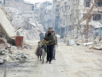 Des civils au milieu de bâtiments détruits à Harasta, au nord-est de Damas, le 30 mars 2018 - STRINGER [AFP/Archives]