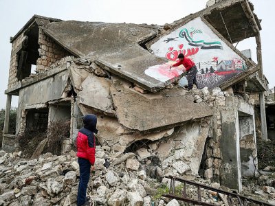 Un homme dessine une colombe de la paix sur une maison détruite et écrit "nous voulons toujours la liberté", le 13 mars 2020 à Binnich, dans la province d'Idleb, dans le nord-ouest de la Syrie - Omar HAJ KADOUR [AFP]