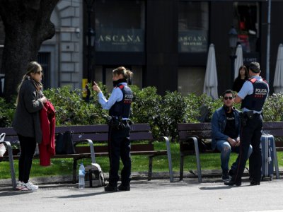 Des agents de police informent des touristes sur les mesures de confinement à Barcelone (Espagne), le 15 mars 2020 - Josep LAGO [AFP]