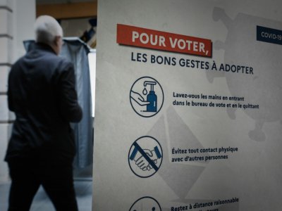 Un votant passe devant une affiche dans un bureau de vote pour le premier tour des élections municipales, le 15 mars 2020 à Paris - Philippe LOPEZ [AFP]