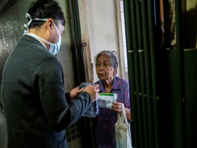 L'élu local pro-démocratie Eason Chan distribue des masques et produits d'hygiène dans un immeuble à Hong Kong le 14 mars 2020 - ISAAC LAWRENCE [AFP]