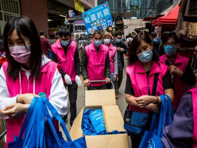 Des partisans de Pékin distribuent des masques dans un marché à Hong Kong le 15 mars 2020 - ISAAC LAWRENCE [AFP]