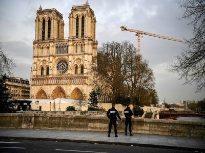 Des policiers patrouillent aux abords désertés de la cathédrale Notre-Dame de Paris, habituellement peuplés de touristes, le 17 mars 2020 - Christophe ARCHAMBAULT [AFP]