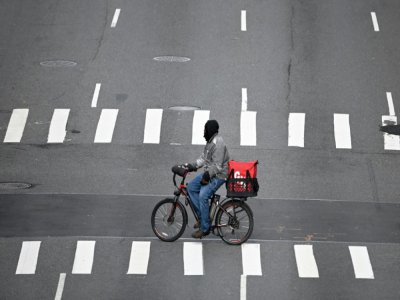 Un livreur à vélo traverse la 1re Avenue, désertée, le 17 mars 2020 à Manhattan - Johannes EISELE [AFP]