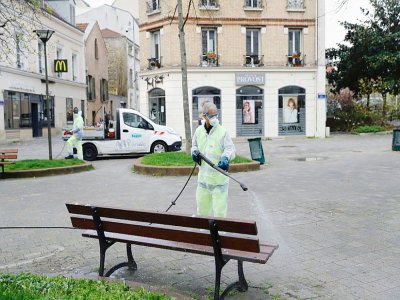 Un employé municipal désinfecte une place de Suresnes, près de Paris, le 18 mars 2020 - Thomas SAMSON [AFP]