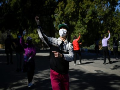 Des femmes portant des masques de protection dansent dans un parc de Pékin, le 13 mars 2020 - WANG ZHAO [AFP]