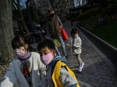 Des enfants, portant un masque de protection contre le coronavirus, jouent dans un parc à Shanghaï, le 17 mars 2020 - Hector RETAMAL [AFP]