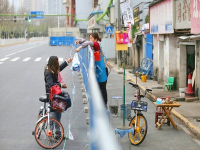 Livraison de nourriture par-dessus une barrière, le 16 mars 2020 à Wuhan, pendant l'épidémie du nouveau coronavirus - STR [AFP]