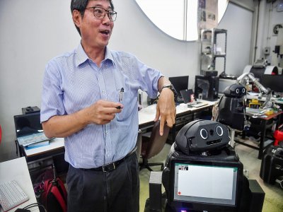 Le professeur Viboon Sangveraphunsiri montre un robot modifié pour s'occuper de malades atteints du coronavirus, le 18 mars 2020 à l'Université de Chulalongkorn à Bangkok - Lillian SUWANRUMPHA [AFP]