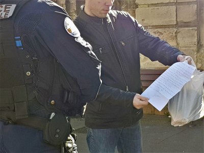 Un policier contrôle l'attestation de déplacement d'un passant dans les rues de Caen.