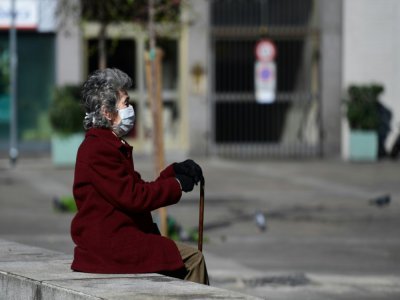 Une dame prend l'air, sur le banc d'une place de Milan, le 8 mars 2020 - Miguel MEDINA [AFP/Archives]