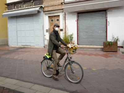 Un homme promène son chien à bicyclette, à Nice, le 17 mars 2020 - VALERY HACHE [AFP]