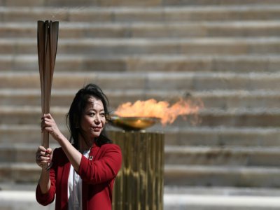 L'ancienne nageuse japonaise Imoto Naoko s'empare de la flamme olympique lors de la cérémonie de sa passation entre la Grèce et le Japon dans un stade pathénaïque vide, le 19 mars 2020 à Athènes - ARIS MESSINIS [POOL/AFP]