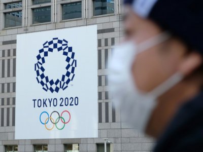 Un passant portant un masque antivirus devant le logo des Jeux olympiques 2020 de Tokyo, le 19 mars 2020 à Tokyo - Kazuhiro NOGI [AFP]