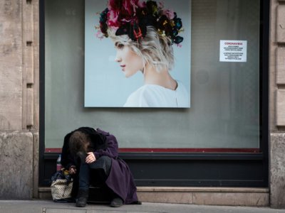 Une personne sans abri devant une boutique fermée pour cause de confinement, le 18 mars 2020 à Paris - JOEL SAGET [AFP]