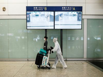 Un passager avec une combinaison de protection, à l'aéroport de Hong Kong le 19 mars 2020 - ANTHONY WALLACE [AFP]