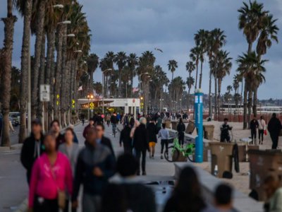 Des promeneurs le long de la plage à Santa Monica, le 19 mars 2020, 20 minutes après l'annonce du confinement par le gouverneur de Californie - Apu GOMES [AFP]