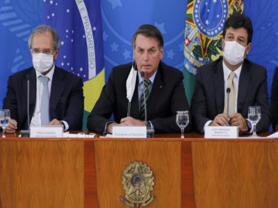 Le président brésilien Jair Bolsonaro (c) entouré de son ministre de l'Economie Paulo Guedes (g) et de la Santé Henrique Mandetta (d), lors d'une conférence de presse à Brasilia, le 18 mars 2020 - Sergio LIMA [AFP]