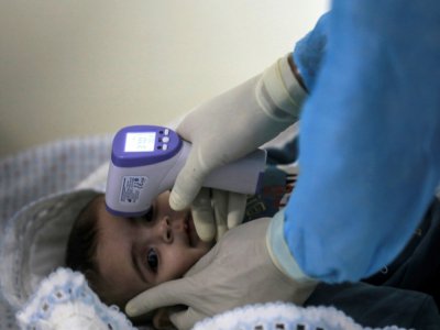 Un enfant palestinien se fait prendre la température dans une école à Gaza, le 18 mars 2020 - MAHMUD HAMS [AFP]