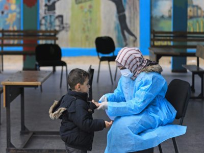 Une Palestinienne prend la température d'un enfant dans une école à Gaza, le 18 mars 2020 - MAHMUD HAMS [AFP]