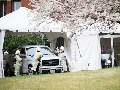 Du personnel médical teste dans les voitures les personnes, sur le parking de l'hôpital John Hopkins à Baltimore, le 19 mars 2020 - JIM WATSON [AFP]