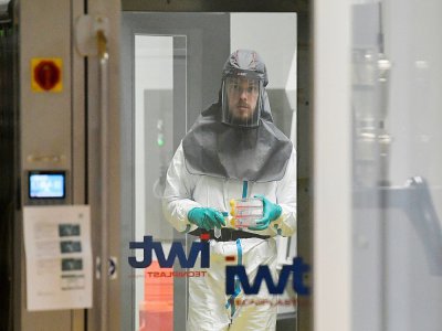 Un virologue travaillant à la recherche d'un traitement contre le coronavirus, détient des échantillons dans un laboratoire de niveau 3 à l'Institut Rega de recherche médicale de l'Université de Louvain, le 28 février 2020 en Belgique - JOHN THYS [AFP]
