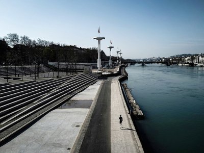 Un homme fait son jogging sur les quais du Rhône à Lyon, le 20 mars 2020 - JEFF PACHOUD [AFP]
