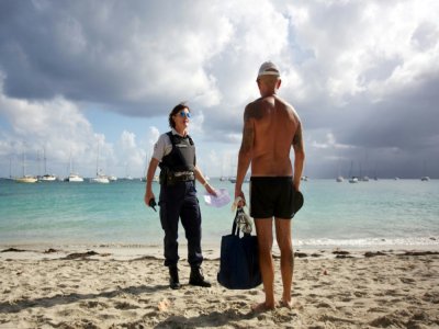 Une policière s'entretient avec un homme après la fermeture d'une plage à Gosier dans le cadre des mesures de confinement imposées par la lutte contre le  coronavirus, le 20 mars 2020 en Guadeloupe - Cédrick-Isham Calvados [AFP]