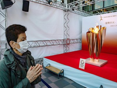 La flamme olympique, sous le regard d'un Japonais portant un masque, lors de son passage à Sendai, au nord du Japon, le 21 mars 2020 - Philip FONG [AFP]