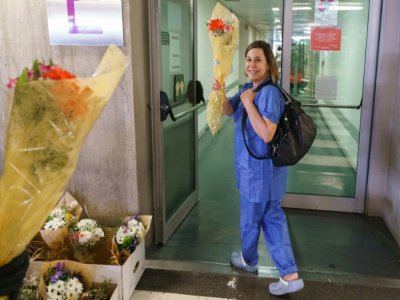 Un membre du personnel soignant de l'hôpital de Burgos (nord de l'Espagne) reçoit un bouquet de fleurs en signe de remerciement, le 21 mars 2020 - CESAR MANSO [AFP]
