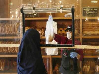Une Palestinienne achète du pain dans une boulangerie de Gaza, où des mesures de précaution ont été mis en oeuvre face au risque lié au nouveau coronavirus, le 22 mars 2020 - MAHMUD HAMS [AFP]