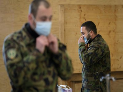 Deux militaires de l'armée suisse enfilent un masque de protection lors d'une formation à Bière (ouest) le 22 mars 2020 - Fabrice COFFRINI [AFP]