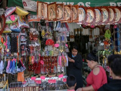 Une femme vend des images religieuses près de la basilique de Guadalupe, à Mexico le 20 mars 2020 - PEDRO PARDO [AFP]
