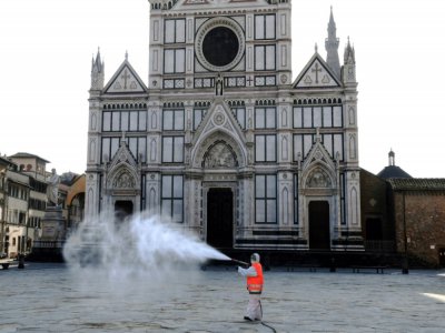 Une employé municipal désinfecte la place Santa Croce à Florence, le 21 mars 2020 - Carlo BRESSAN [AFP]