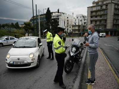 Contrôles policiers auprès d'un automobiliste et d'un piéton, à Athènes le 23 mars 2020 - Aris MESSINIS [AFP]