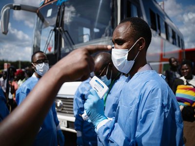 Un membre du Centre biomédical du Rwanda prend la température des passagers à un gare routière à Kigali, le 22 mars 2020 - Simon Wohlfahrt [AFP]