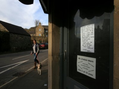 Un passant passe devant une boutique fermée dans le village d'Eyam, dans le Nord de l'Angleterre, le 23 mars 2020. - Lindsey Parnaby [AFP]
