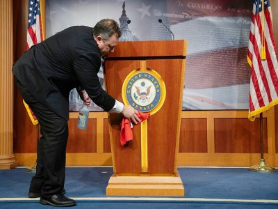 Un employé désinfecte le pupitre de la salle de presse du Sénat américain,
à Washington, le 17 mars 2020 - SAUL LOEB [AFP]