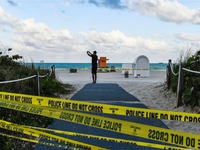 Un touriste franchit les barrières d'interdiction au plages de Miami Beach, le 19 mars 2020 - CHANDAN KHANNA [AFP]