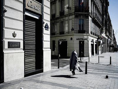 A Paris sur les Champs-Elysées désertés par ses flâneurs et touristes, un sans domicile fixe erre, le 23 mars 2020 - Philippe LOPEZ [AFP]