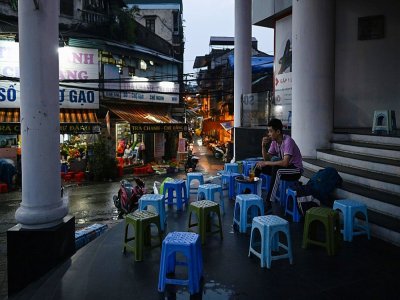 A Hanoï, au Vietnam, un homme seul assis à un café de rue désert, le 23 mars 2020 - Manan VATSYAYANA [AFP]