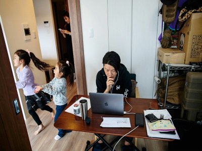A Tokyo, une employée télétravaille pendant que ses enfants jouent dans l'appartement, le 23 mars 2020 au Japon - Behrouz MEHRI [AFP]